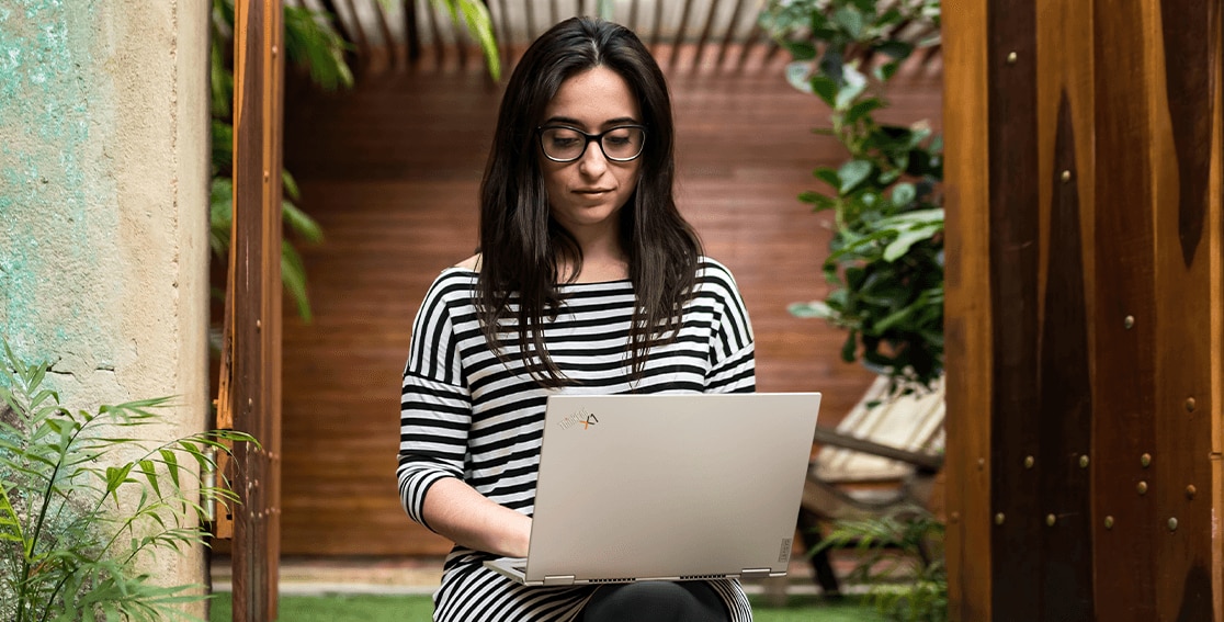 Rearview of Lenovo ThinkPad Titanium Yoga laptop in use on a woman’s lap, open more than 90 degrees. 