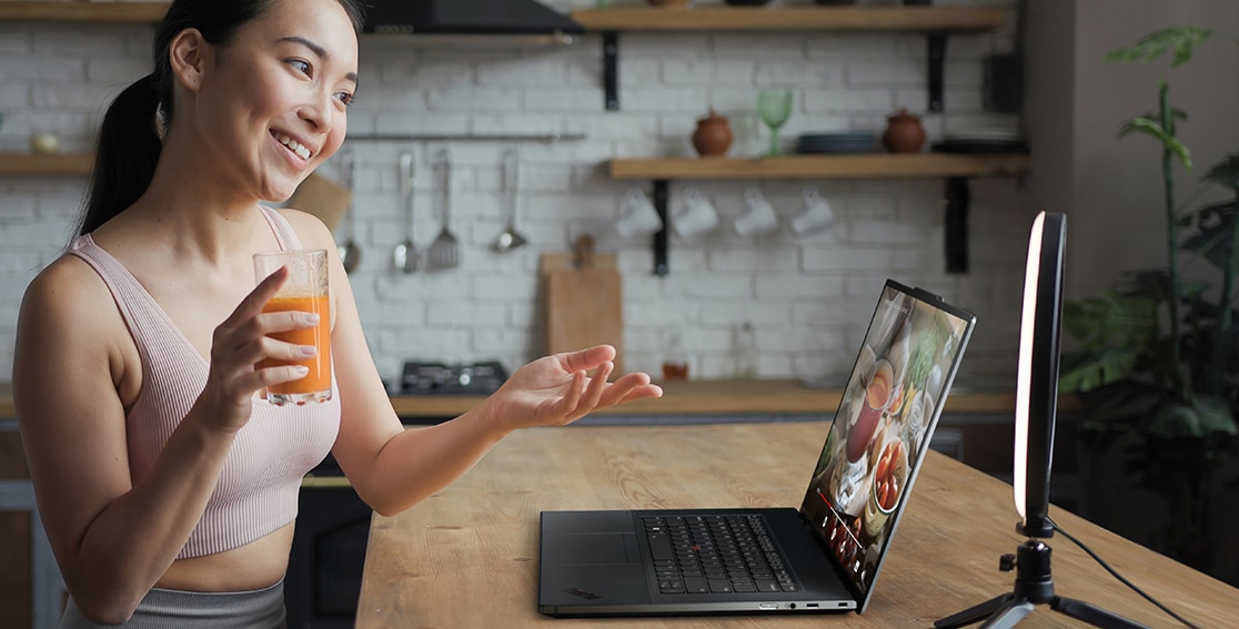 Person at a table using Lenovo ThinkPad Z16 laptop to create video post on social media. 