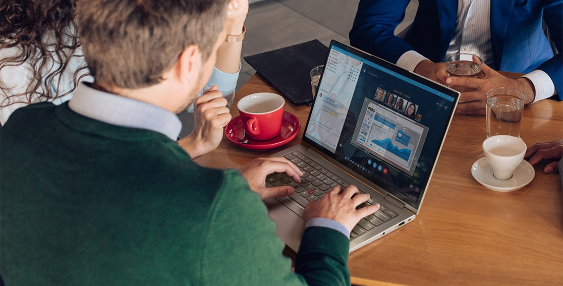 People around a table with someone videoconferencing on the Lenovo ThinkPad X1 Yoga Gen 7 2-in-1 laptop showing display and keyboard.