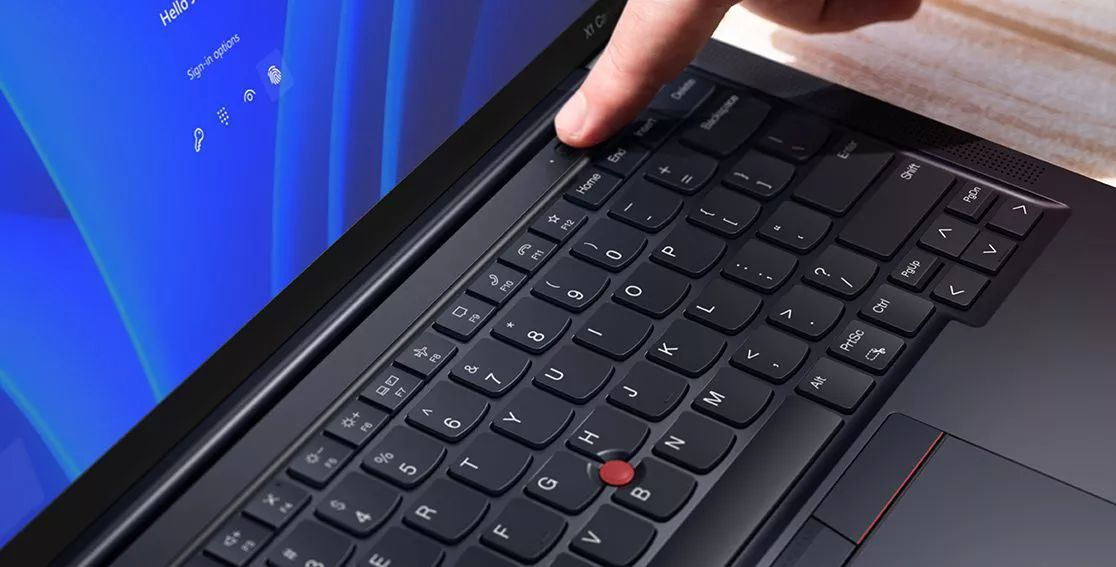 Gros plan d’un doigt touchant le bouton de mise sous tension avec lecteur d’empreintes digitales intégré du portable Lenovo ThinkPad X1 Carbon Gen 11.
