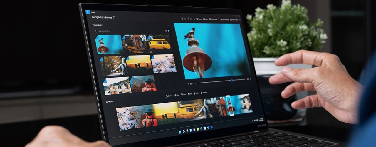Gros plan de mains interagissant avec le portable Lenovo ThinkPad X1 Carbon Gen 11 ouvert et montrant des images et une vidéo à l’écran.