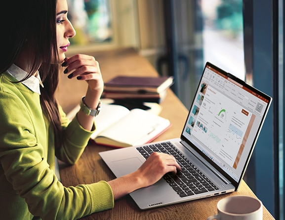 Woman at a café window working on an IdeaPad Slim 5 Gen 8 laptop