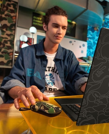 Modèle tenant la souris à côté de l'ordinateur portable.