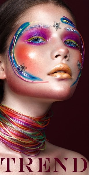 Une femme avec des peintures colorées sur le visage et plusieurs colliers au cou