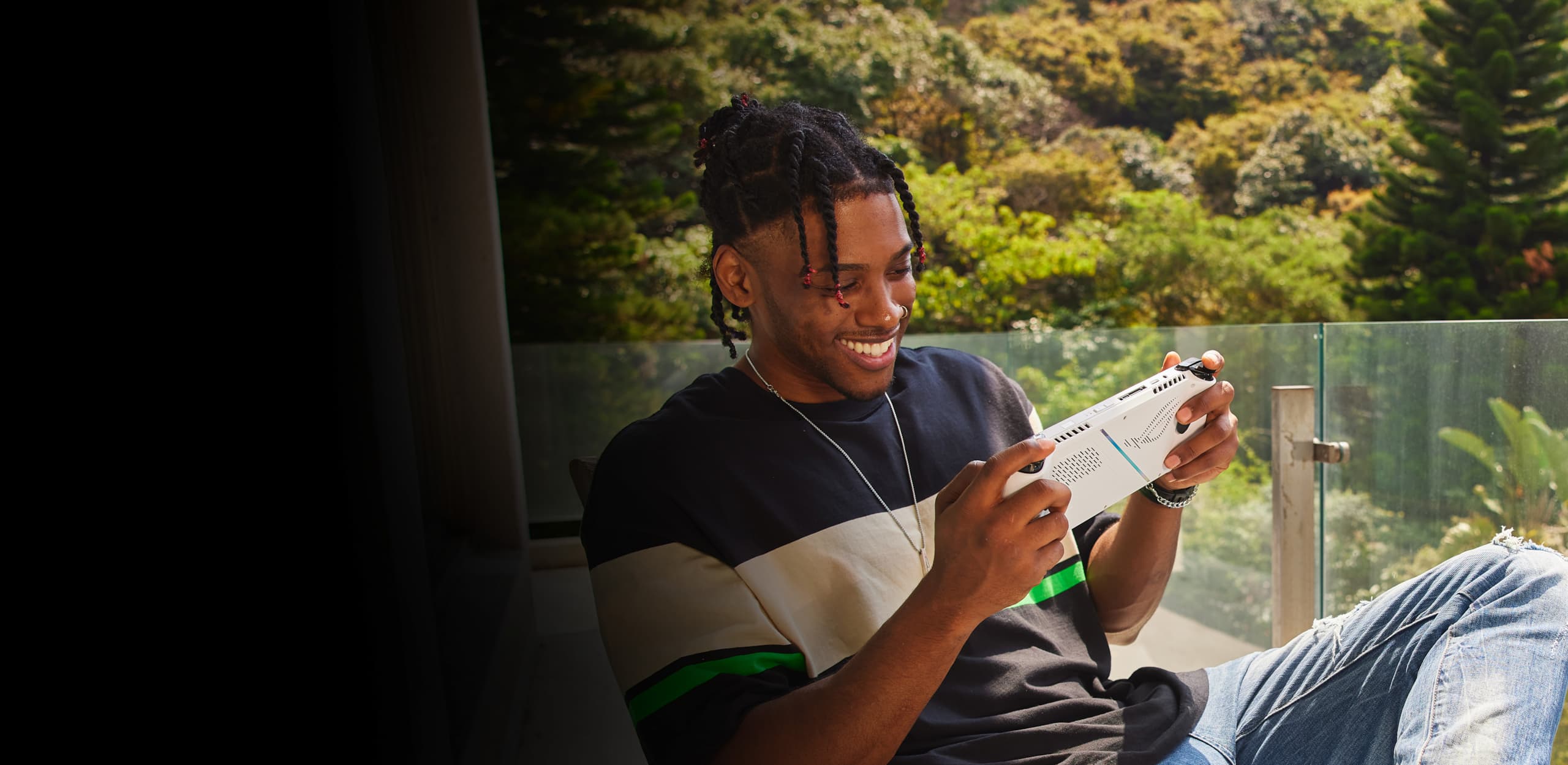 Personne assise sur une chaise à l'extérieur et souriant tout en jouant avec la ROG Ally.