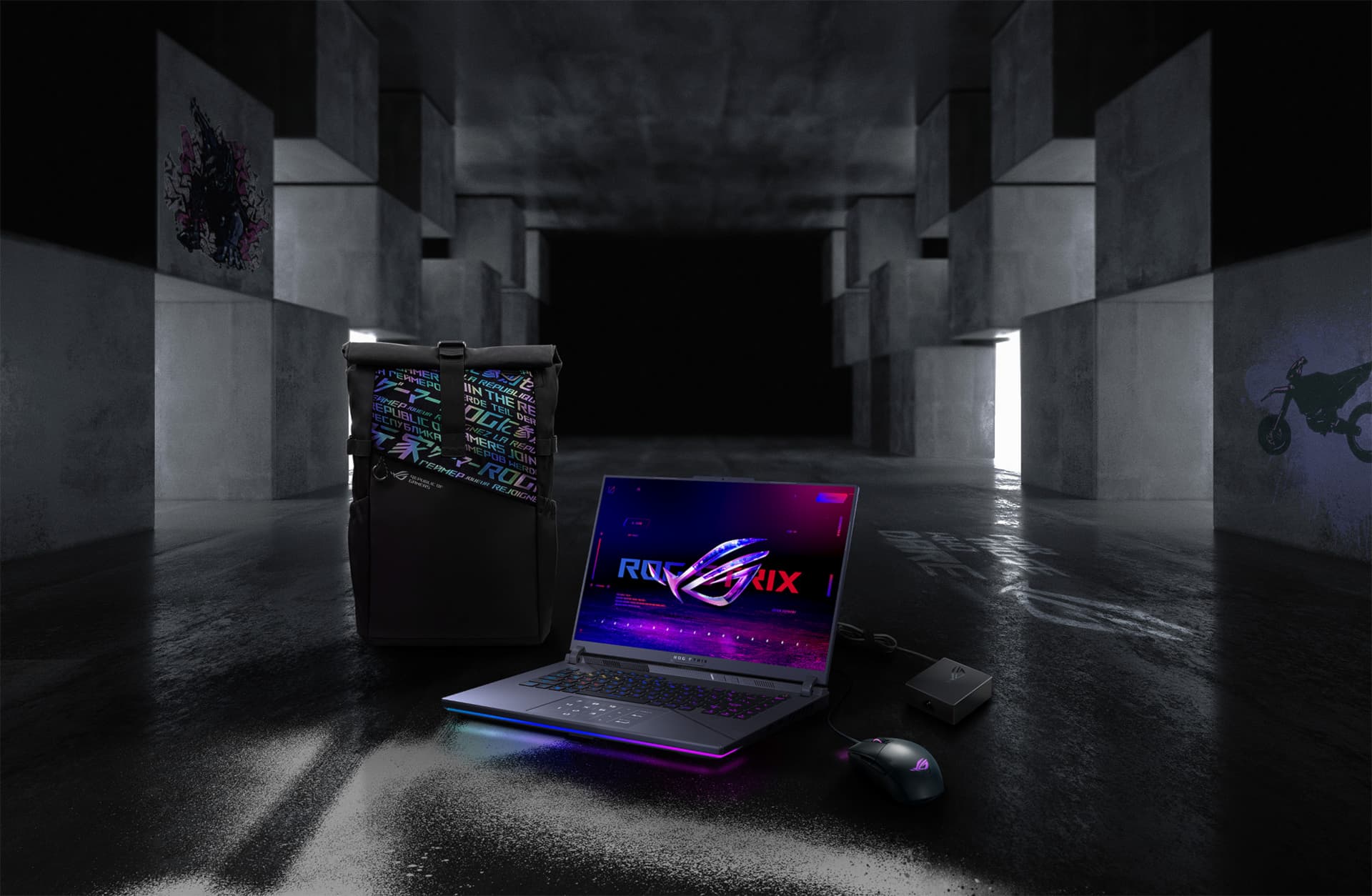 Dans un grand espace souterrain, de gauche à droite : un sac à dos ROG, un G16, une souris ROG Strix Gladius III et un adaptateur 100W.