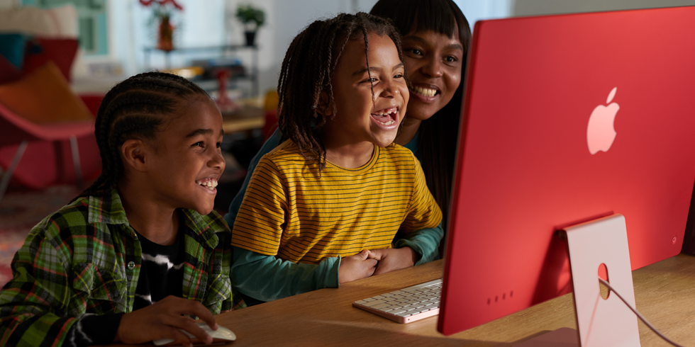 Une famille en train de rire en regardant une émission sur un iMac.